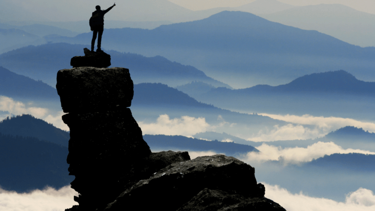 A man celebrating his success at the top of mountain.