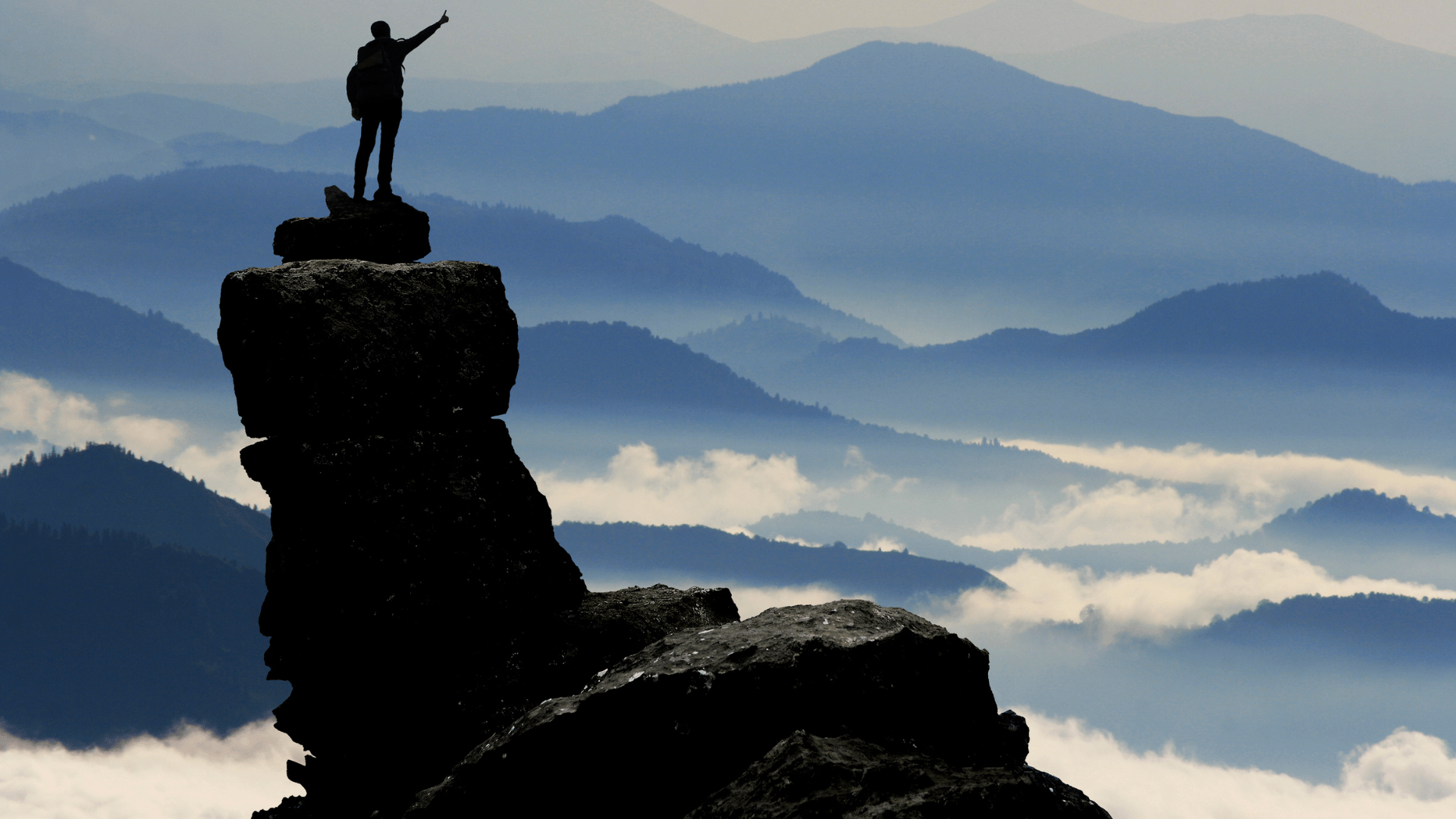 A man celebrating his success at the top of mountain.