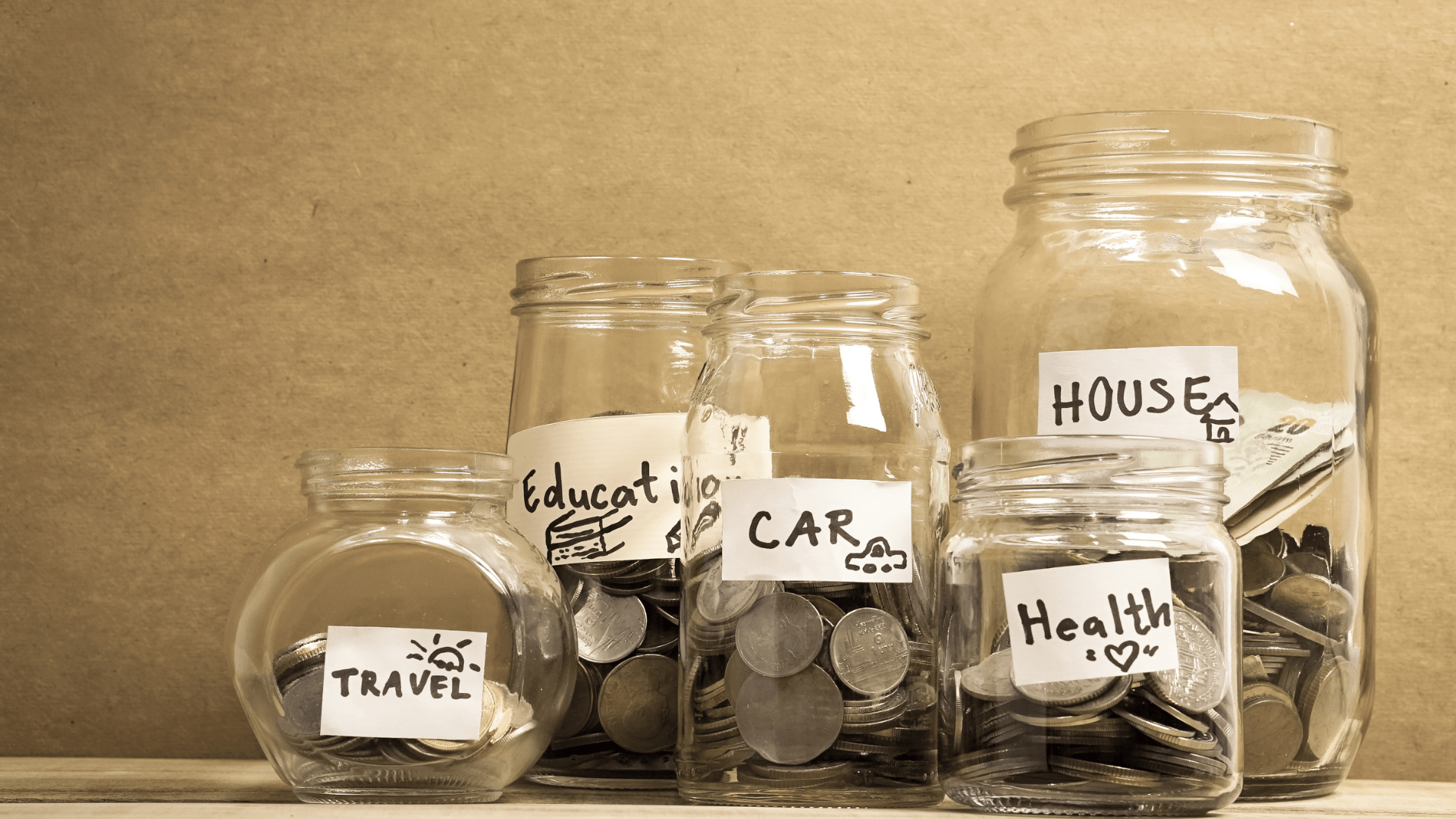 An image of a collection of jars of money labeled with household. expenses