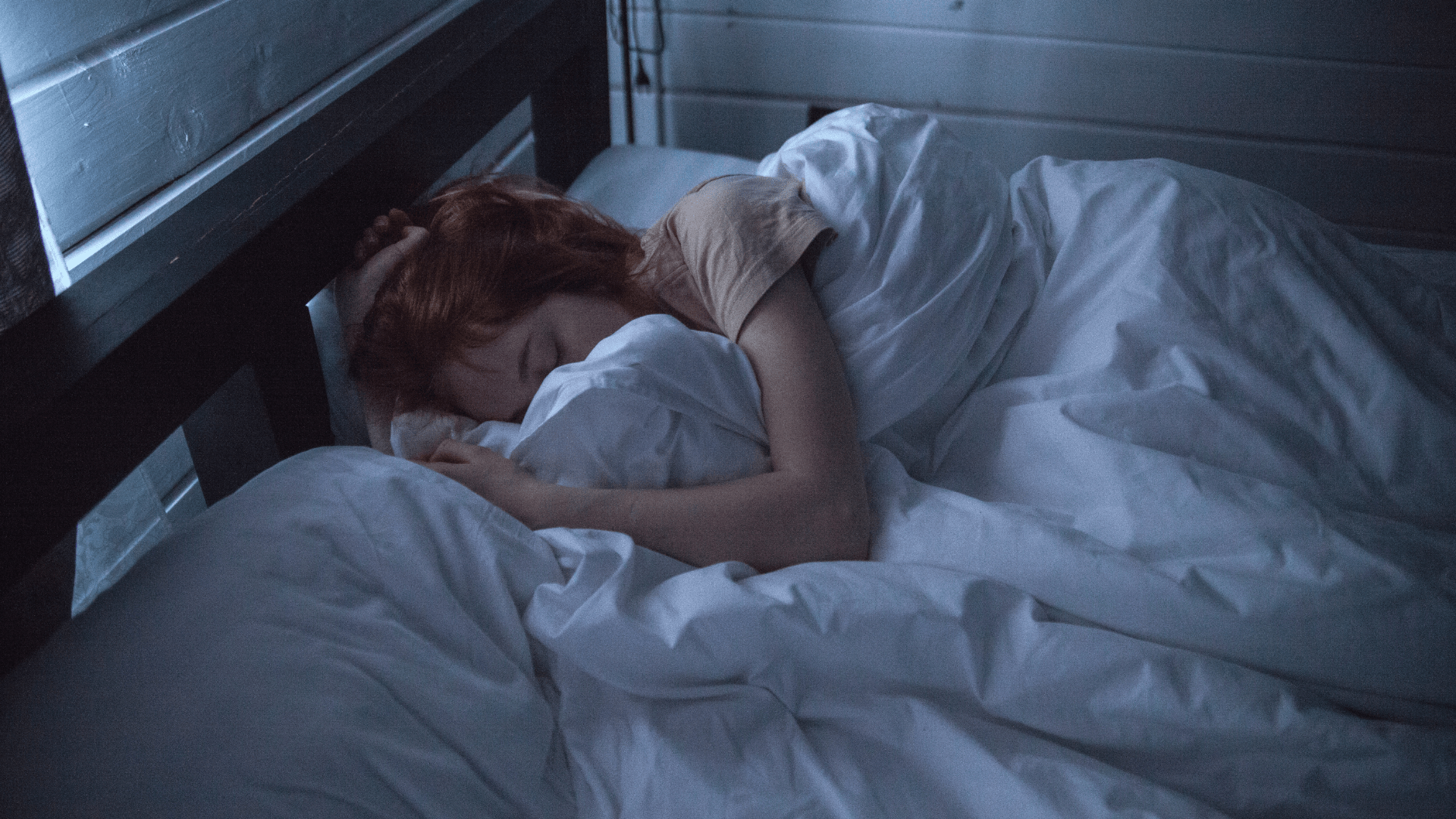 A woman curled up in bed.
